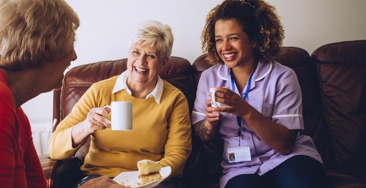 two old women in a care home laughing with their nurse